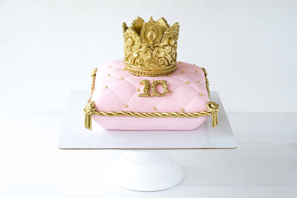 istock Cake pillow decorated with golden crown on a white background for a princess 1283914280