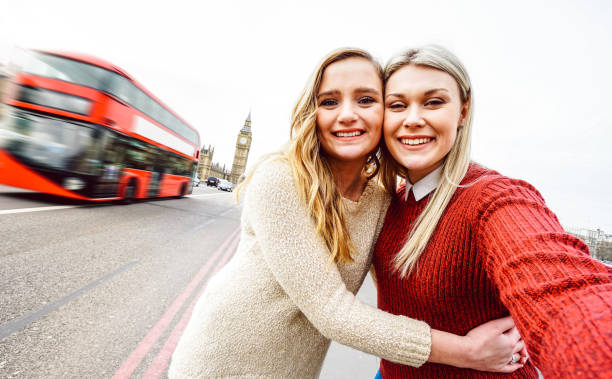 female friendship concept with girls couple taking selfie outdoors in london - lgbtq genuine love relationship with happy millenial women girlfriends having fun together - bright warm filter - bus family travel destinations women imagens e fotografias de stock