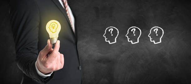 istock businessman holding a lit lightbulb in front of a blackboard 1283917548