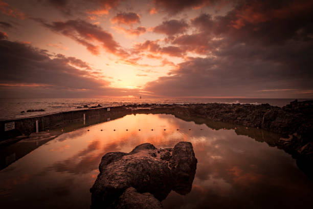 sunset reflection on natural swimming pool on la reunion island, mascarene islands, indian ocean, french overseas territory.