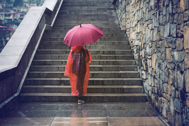 Young woman with umbrella going up the stairs in a rainy autumn day