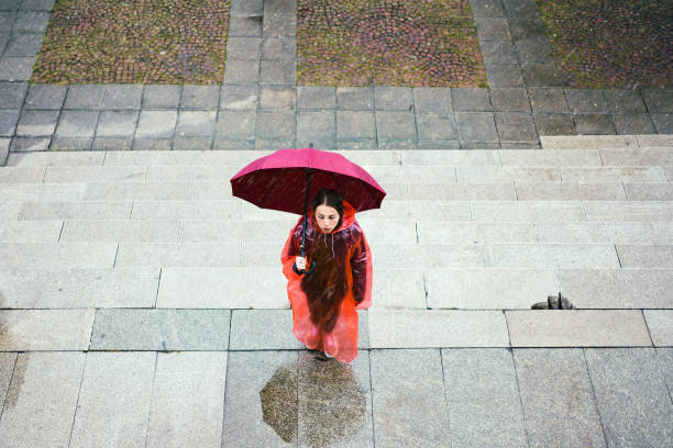 Young woman with umbrella standing in the autumn rain