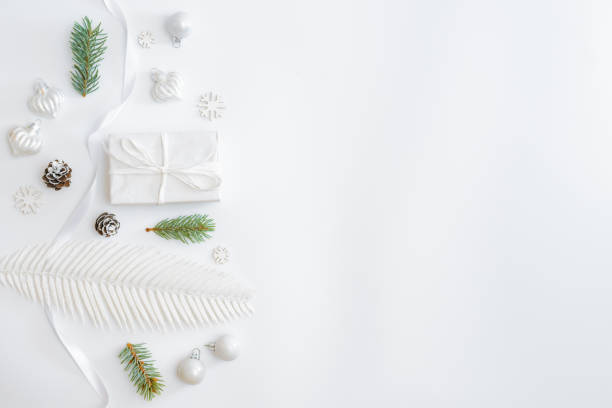 istock Flat lay frame with fir branches, christmas baubles decoration and gift box on a white background 1283918045