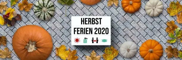 autumn decoration with pumpkins and colorful leaves and German message for FALL BREAK 2020  on stone pavement background