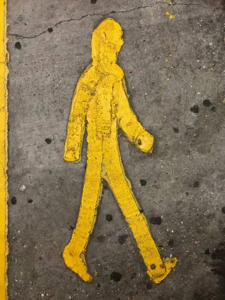 a Sign of a yellow person walking on the floor in a parkinglot
