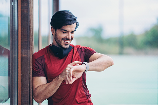 Smiling sportsman with face mask and smart watch