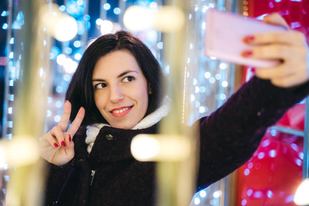 istock Woman making selfie among Christmas string lights 1283925530