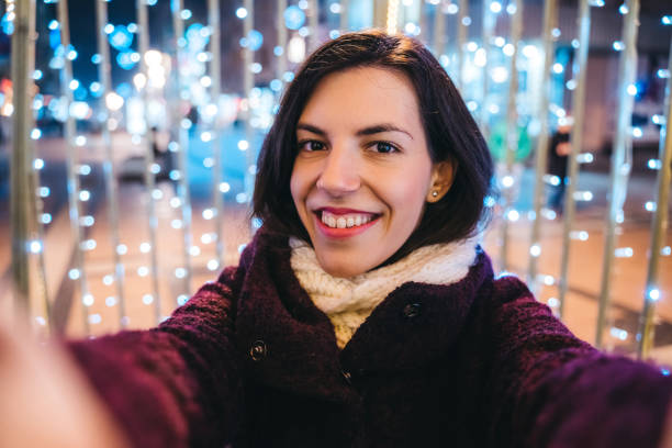 istock Woman making selfie among Christmas string lights 1283925548