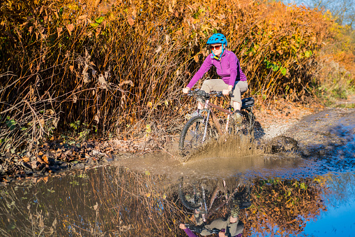 Sunny day and Autumn colors with mature woman bicycle riding on muddy road. It is in The Ljubljana Marshes, which are located near Ljubljana in Slovenia, Europe.