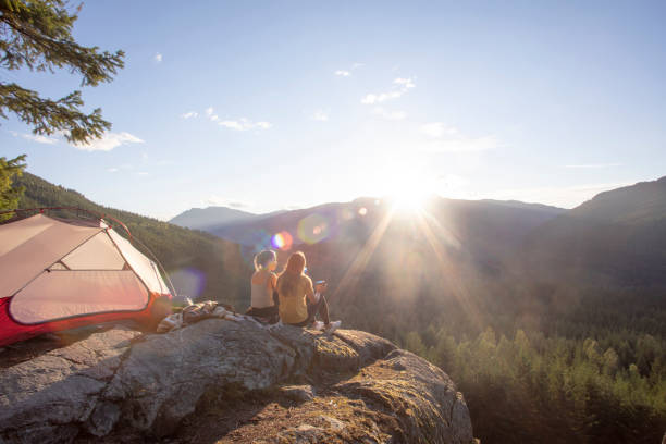 istock Young women watch the sunset on a mountain ledge campsite 1283929193