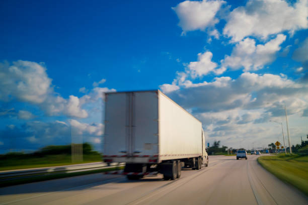 istock White semi-truck  with container cargo driving on a rural way 1283934382