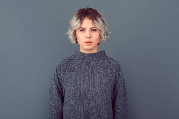 mujer joven en una imagen de estudio suéter gris aislado en el fondo gris serio - ombré fotos fotografías e imágenes de stock