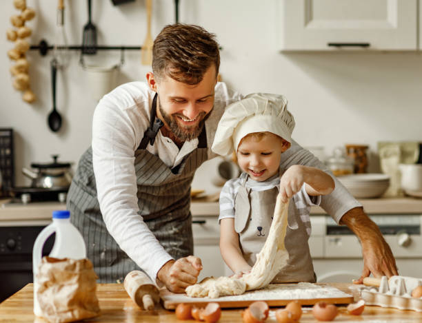 Father and little boy kneading dough together