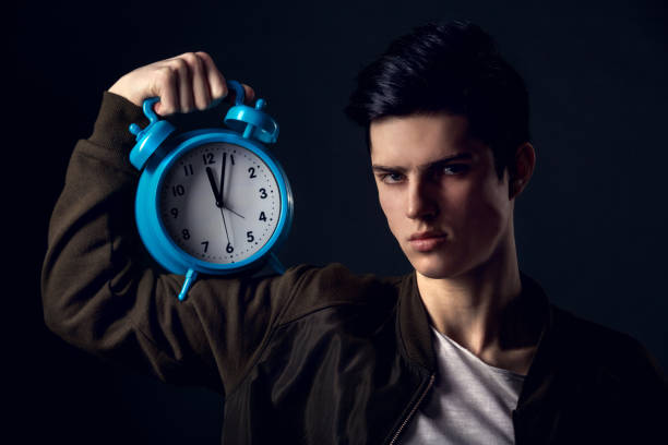 istock Young man isolated on a grey wall studio concept showing time 1283939378