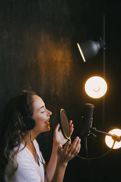 istock Young beautiful woman singing in microphone, recording voice in a studio. 1283940693