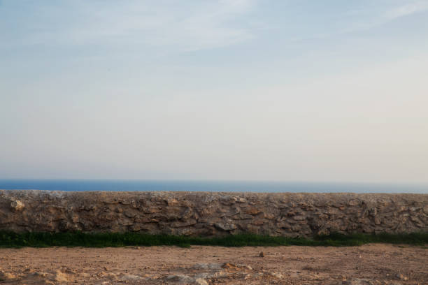 horizontal image formed by stone wall, land, grass, sea and sky,