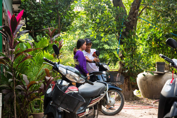 image de la ville de phnom penh. image de coulpe de filles détendues à côté de leur moto près de la forêt. - coulpe photos et images de collection