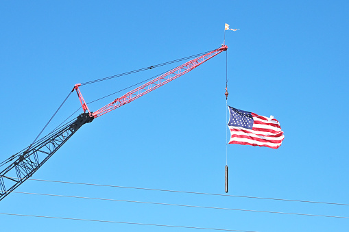 American flag hanging from tall construction crane.