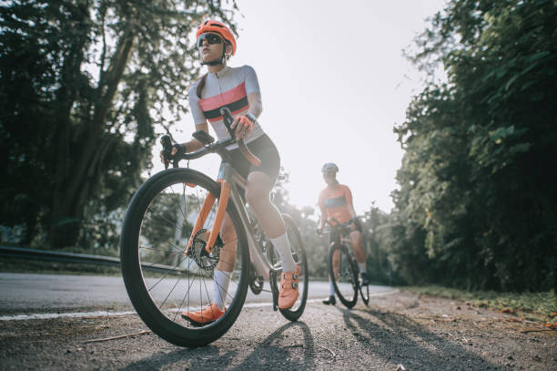 angolo basso 2 asiatica cinese donna ciclismo bici da strada in bicicletta nella zona rurale al mattino preparandoti a pedalare - cyclist cycling road women foto e immagini stock