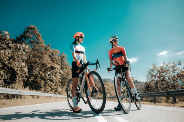 asian chinese woman road bike cyclist leaning on road divider resting - road cycling imagens e fotografias de stock