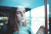 sad lonely young woman looking thoughtfully through window