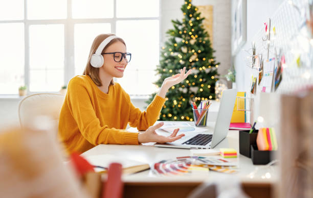 istock Happy young woman freelancer in headphones working remote, communicates via video link, makes a video call  at laptop at home before Christmas 1283950743