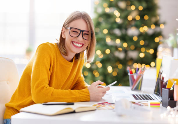 istock Happy  young woman freelancer laughs while sitting at a workplace with a phone in her hands in a home office working remote  before Christmas 1283951352