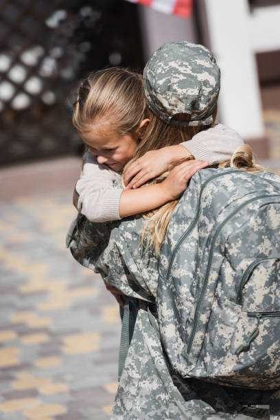 istock Smiling daughter hugging mother in military uniform on blurred background 1283956731
