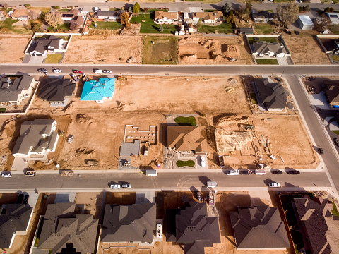Drone view of a subdivision with already completed homes with families living in them, new construction, and lots prepared for construction