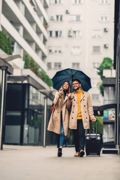 istock beautiful smiling young couple walking in the rain 1283963505