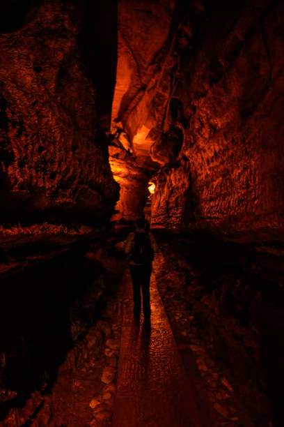 istock Woman Hikes Through Dimly Light Cave Tunnel 1283964560