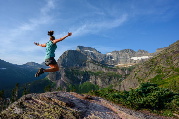 женщина прыгает с видом на ледник гриннелл - exploration mountain ice jumping стоковые фото и изображения