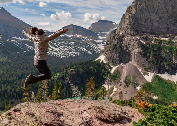 女性はグリンネル湖の上に喜びのためにジャンプ - exploration mountain ice jumping ストックフォトと画像