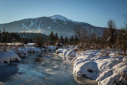 Frozen river of the golden dreams in sunny cold day in Whistler valley.