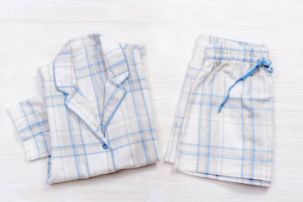 白い木の青いチェックやストライプの折り畳まれた暖かい白いパジャマ