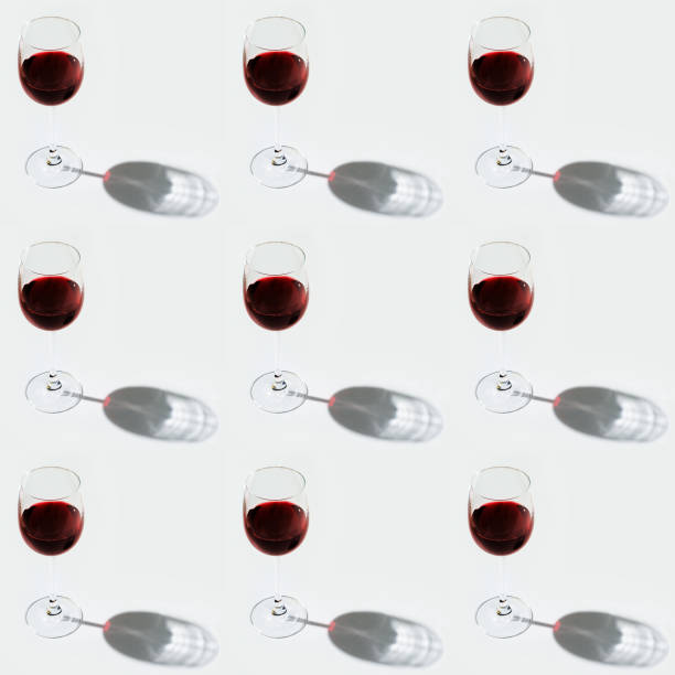 Seamless regular creative pattern with glass of red wine on light with dark shadow. Printing on fabric, wrapping paper.
