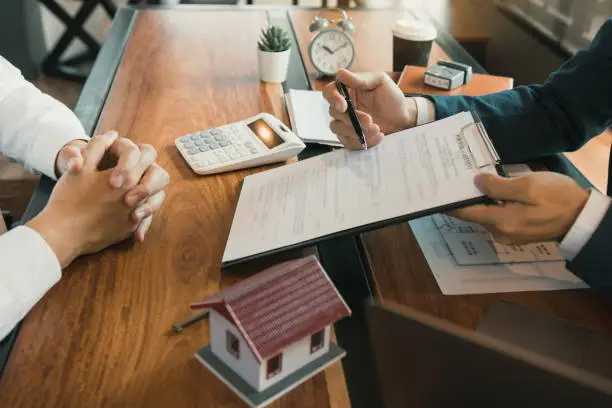 Agents are using pens pointing to contracts and are being explained to customers at the office.