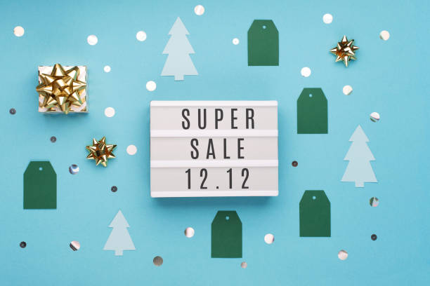 istock 12.12 Super Sale text on white lightbox, with gold gift box and Christmas decorations on blue paper background. 1283984927