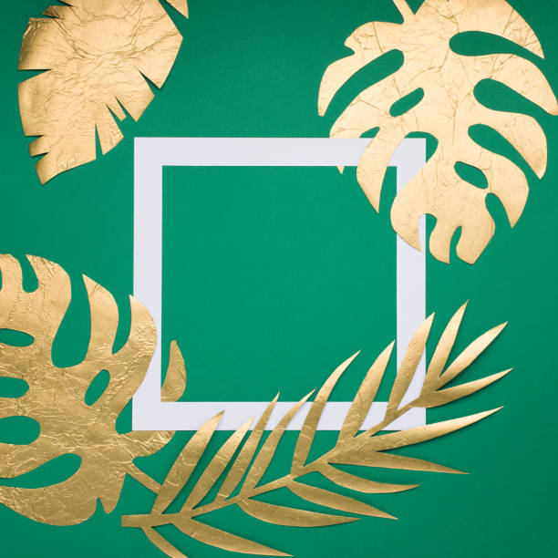 istock Golden tropical leaves Monstera and empty paper white frame on green background. 1283984945