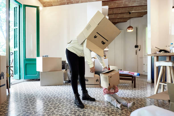istock Mother and Young Daughter Playing with Boxes on Moving Day 1283992323