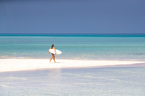 A surfer on a beach in a dreamlike tropical environment