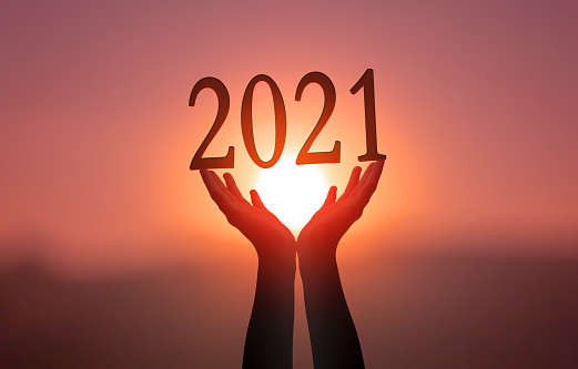 Concepto 2021: Las manos sostienen 2021 en el fondo de la puesta del sol photo