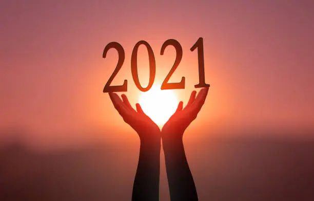 Photo of 2021 concept: Hands hold  2021 against on sunset  background