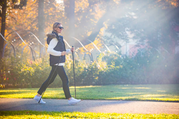 Middle-aged woman nordic walking in city park People nordic walking in city park nordic walking pole stock pictures, royalty-free photos & images
