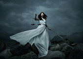 Young fairly woman with scale and sword over the dramatic sky