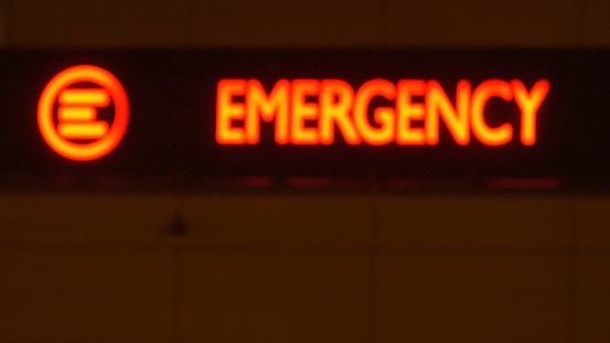 Emergency Department Service Red Sign on Hospital Building at Night Defocused