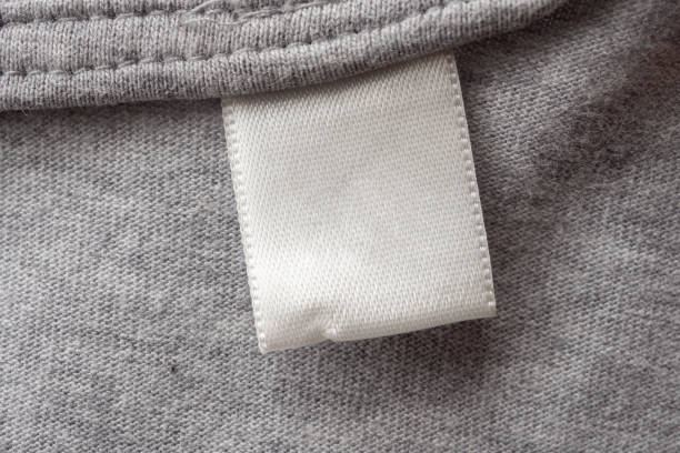 istock Blank white laundry care clothes label on gray fabric texture background 1283999014