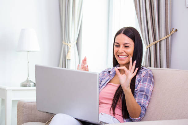 istock Attractive happy young woman sitting on the sofa using laptop computer, having video chat, waving, talks with her friend about coronavirus and stay home during online video call. Working home 1283999041