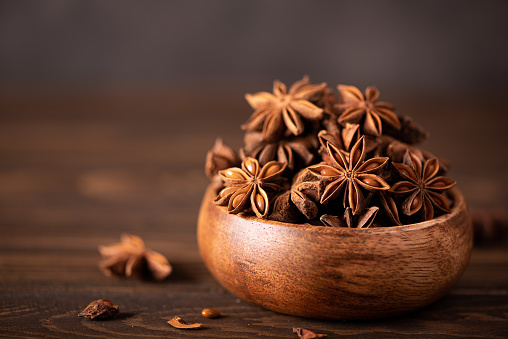 star anise in a wooden bowl on the table, close up