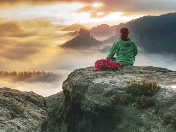 istock Alone Girl Sits With Her Back On A Cliff Against Huge Misty Mountain 1284000301